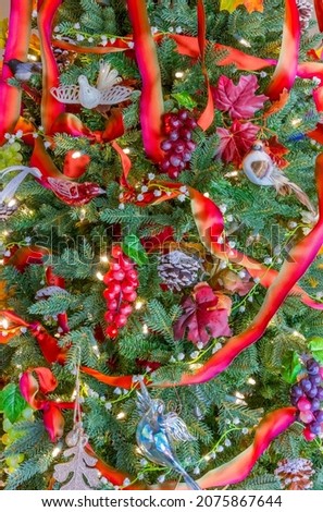 Birds, grapes,  fall leaves and ribbon garland fill a Christmas tree, good for autumn and Christmas.