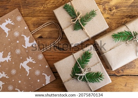Christmas gifts wrapped in eco-friendly paper and a gift craft bag on a wooden table. Christmas flat lay. Festive background for the New Year's sale