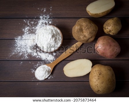 Potato starch with potatoes on a dark wooden background. Royalty-Free Stock Photo #2075873464