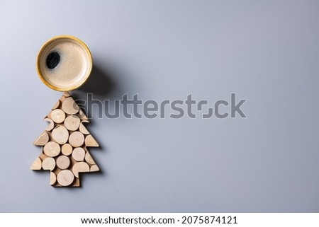 Creative background made of wooden Christmas tree and coffee cup on gray. Christmas eco frienly card. Sustainable lifestyle, plastic free holidays concept. Nature New Year concept. Copy spase
