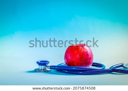 Healthcare concept - stethoscope and red apple on blue background with copy space
