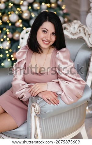 Beautiful woman in a pink dress near the Christmas tree