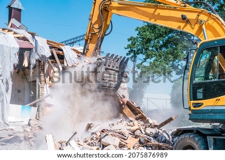 Excavator bucket breaks old house. Building demolishing for renovation Royalty-Free Stock Photo #2075876989