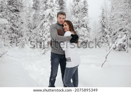 Young hipster couple hugs each other in a winter park. Winter holidays. Christmas holidays outdoors in the forest