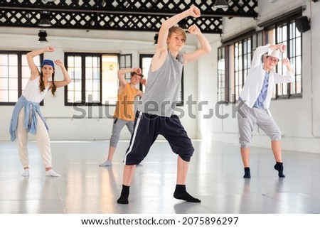 One young lady and few boys dancing modern dance on rehearsal