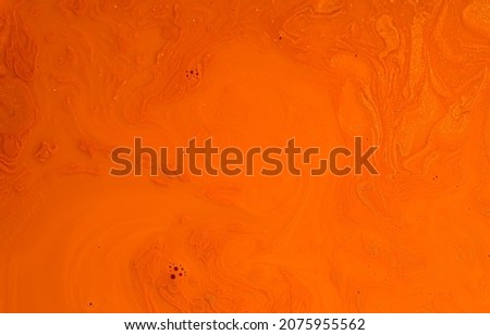Abstract bright orange shadowy background of swirls with an abstract pattern of bubbles created by a mixture of paint colours in a milk base.