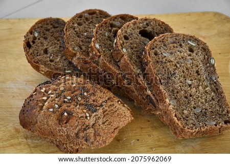 Sliced rye bread with sunflower and poppy seeds on rustic wooden background. Healthy food still life