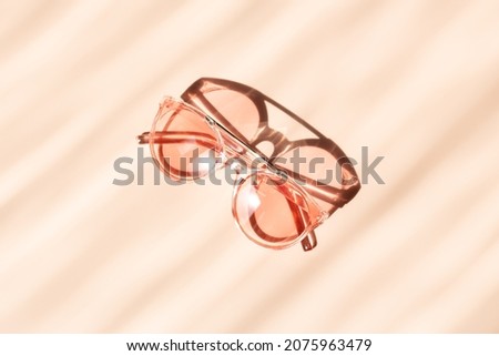 Fashionable pink sunglasses on beige background. Concept of summer accessorize