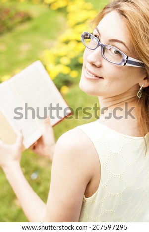 Portrait of a beautiful young woman reading a book in nature.