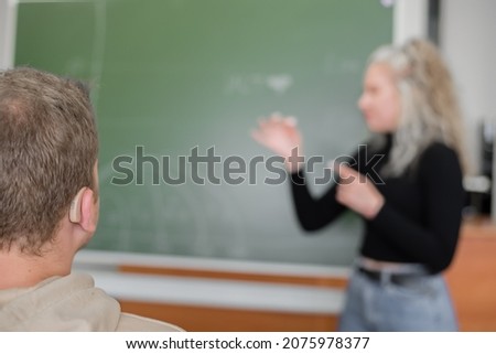 The girl and the guy are talking in Russian sign language. Three deaf students chatting in a university class