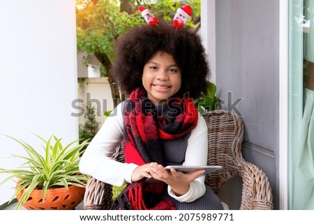 Happy little smiling african american girl using tablet for Learning online at living room.