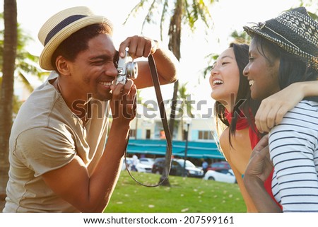 Man Taking Photograph Of Women In Park