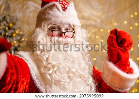 Santa claus using mobile phone during christmas time takes selfie or communicates via video communication. A luxory christmas gift or a gift for good behavior. New year.