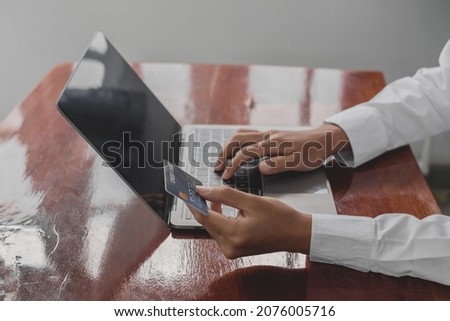 The businessman's hand is holding a credit card and using a laptop for online shopping and internet payment.