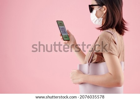 Young woman in medical mask receiving digital COVID-19 certificate on smartphone
