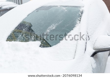 A snow-covered car stands on the street in winter. Snow on car windows