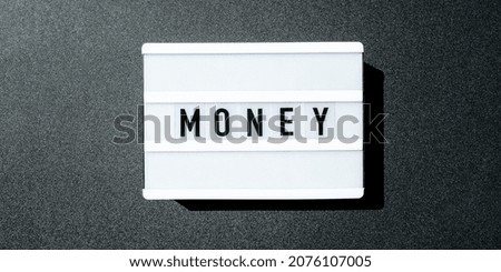 Lightbox board on a black background with the words MONEY in black letters. Currency, cash