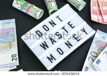 Lightbox board with word DONT WASTE MONEY in black letters around euro banknotes. Money, Business, finance, investment, saving. Cash bill. Business budget of wealth and prosperity finance. Passive 