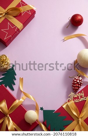Red gift box with yellow ribbon and christmas ornament , candy with pine tree and twinkle pearl in purple background , photography holiday content , top view