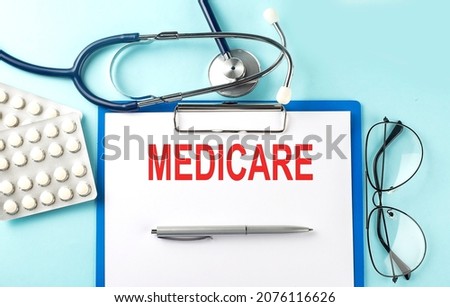 Paper with text MEDICARE on blue background with stethoscope and pills