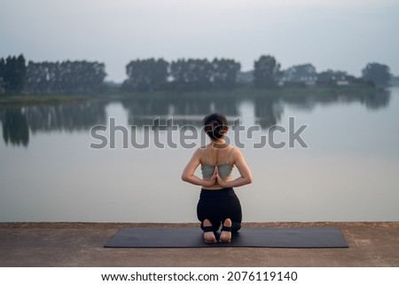 the girl is doing yoga by the lake