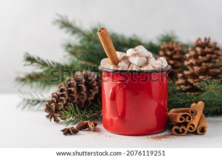 Cup of hot cocoa with marshmallow and cinnamon stick surrounded by spruce branches. Cozy seasonal holidays. White background
