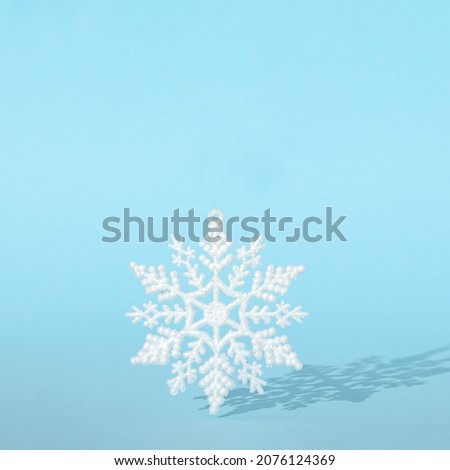 creative Christmas snowflake with sunny shadow against pastel blue background. minimal modern surreal creative idea with copy space.