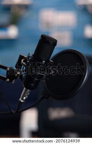 Closeup of professional podcast microphone standing on desk table in podcasting studio equipped with recording equipment. Digital web internet streaming station. On-air show
