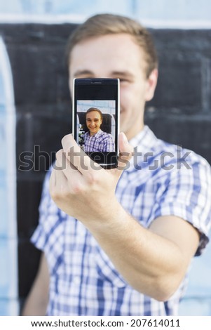 Young fashionable hipster man with sunglasses taking a selfie outdoors