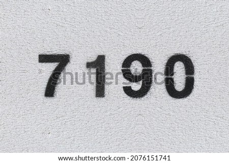 Black Number 7190 on the white wall. Spray paint. Number seven thousand one hundred ninety.