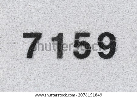 Black Number 7159 on the white wall. Spray paint. Number seven thousand one hundred and fifty nine.