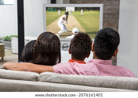 Rear view of family sitting at home together watching cricket match on tv. sports, competition, entertainment and technology concept digital composite image.