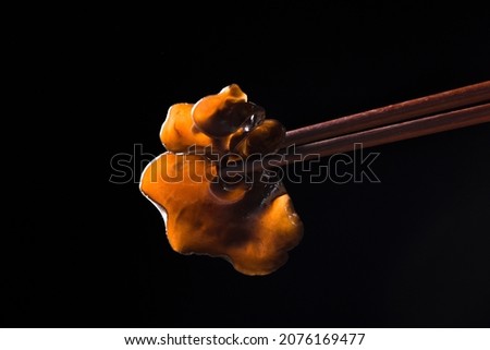 Chopsticks with black fungus on black background, close up Royalty-Free Stock Photo #2076169477