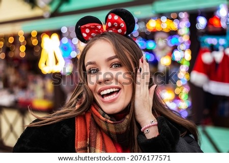 Young pretty smiling open mouth white teeth woman gesturing celebrating dressed warm sheepskin coat laugh. Cold weather, winter market holidays fair, travel resort. New Year Christmas decorations