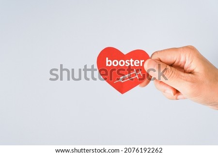 senior  hand holding red heart paper shape with booster word and syringe icon for vaccinated or inoculation booster dose due to spread of corona virus, population, social or herd immunity concept Royalty-Free Stock Photo #2076192262