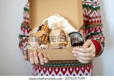 Preparing self care package. Children hand are holding Seasonal gift box. Eco-friendly gift for family and friends for Valentine's Day, Thanksgiving and Christmas. Copy space
