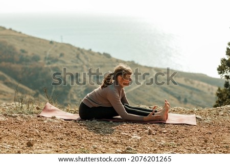 An elderly woman does yoga in nature