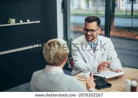 Smiling male doctor in consultation with a senior woman patient in a modern office Royalty-Free Stock Photo #2076202267