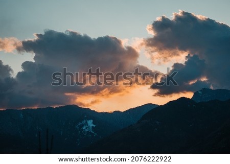 Orange clouds above the snow covered mountains of Kullu Valley as seen from the Bijli Mahadev Temple during the sunset at Kullu in Himachal Pradesh, India.  Royalty-Free Stock Photo #2076222922