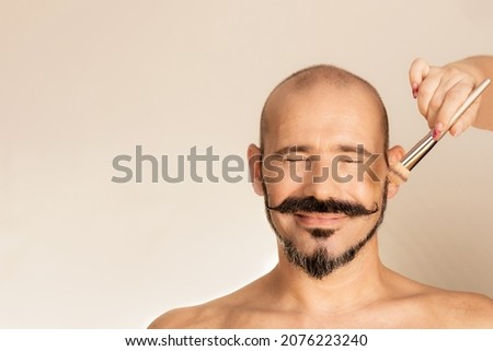 Cosmetics for men's makeup. Cosmetics for the face. Woman's hands with a brush. Happy bald and bearded man.
