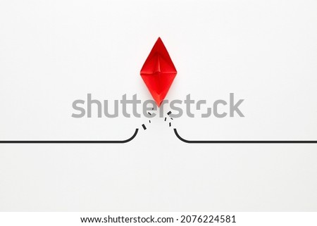 Red paper boat transcends the barrier. To overcome difficulties, problems or boundaries in business concept Royalty-Free Stock Photo #2076224581