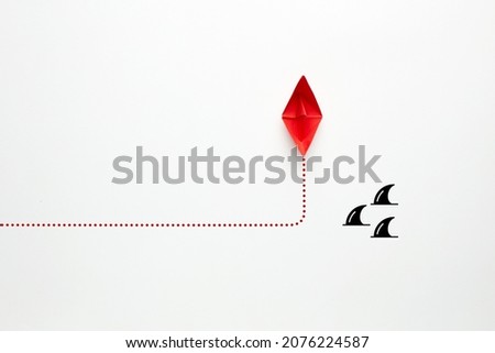 Red paper boat changes direction against sharks on white background. Risk or danger avoidance in business concept. Royalty-Free Stock Photo #2076224587