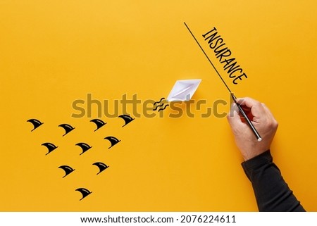 Insurance, security or safety concept. Sharks chase a paper boat sailing towards the insurance line. 