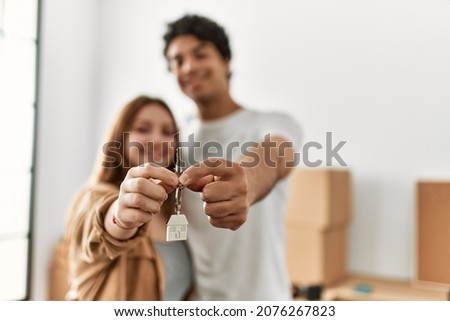 Young couple smiling happy holding key of new home. Royalty-Free Stock Photo #2076267823