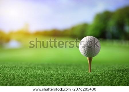 Close-up golf ball on tee with fairway golf course background.