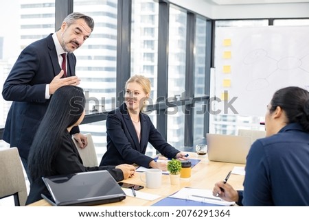 Businessman explaining new business ideas to peers in conference room during meeting at office.