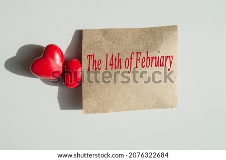 The inscription on February 14 on wrapping paper and two red hearts symbolize love, Valentine's Day, a romantic couple.
