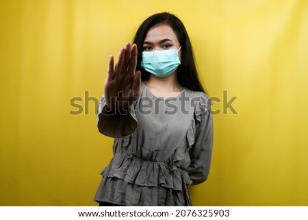 Beautiful young woman wearing a mask with open arms, refusing something, isolated
