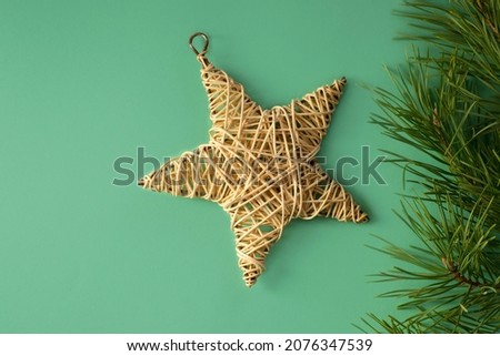 Banner with rattan star and pine branches on a green background. Christmas picture with free space for text. Natural wooden rattan star. 