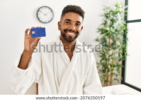Young african american holding credit card at beauty center.